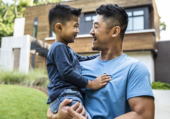 Father holding son in front of modern home
