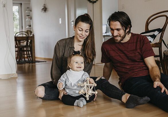 Happy family with baby girl sitting on the floor at home