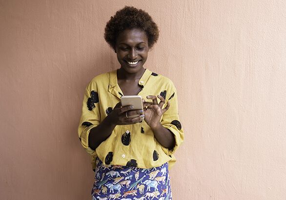 A woman in yellow shirt holding a cell phone.