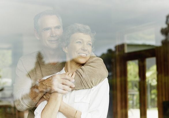 A man and woman hugging in front of a window.