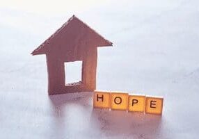 A small house with the word hope spelled out in scrabble tiles.