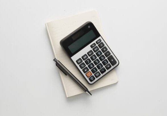 Black calculator and pen on closed cream notebook