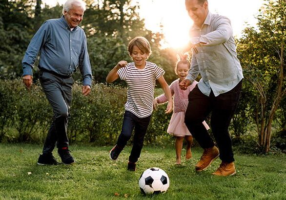 Full length of multi-generation family playing soccer in backyard