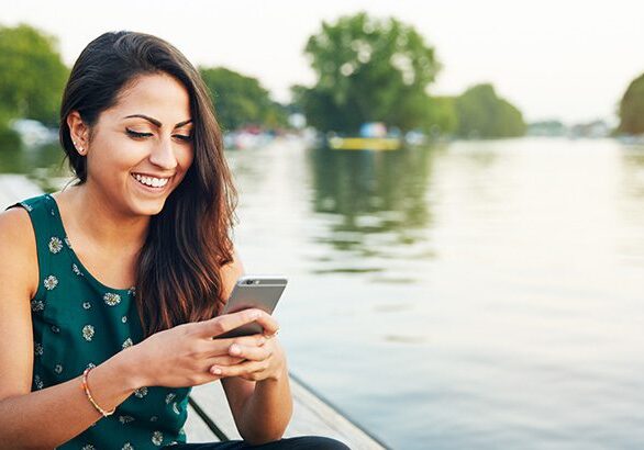 Young woman with smartphone on jetty.
